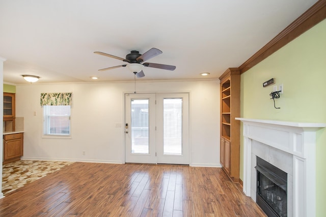 unfurnished living room with ceiling fan, ornamental molding, and wood-type flooring