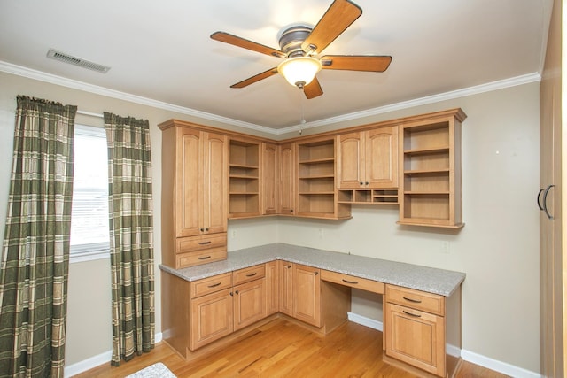 unfurnished office featuring crown molding, a healthy amount of sunlight, built in desk, and light hardwood / wood-style flooring