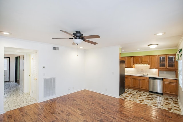 unfurnished living room with sink, crown molding, ceiling fan, and light wood-type flooring