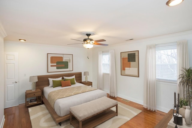 bedroom with hardwood / wood-style flooring, ornamental molding, and multiple windows