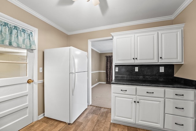 kitchen featuring crown molding, light hardwood / wood-style floors, white cabinets, and white refrigerator