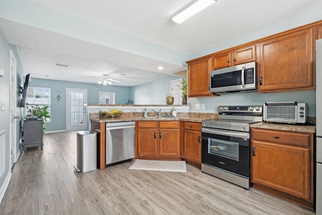 kitchen featuring sink, light hardwood / wood-style flooring, kitchen peninsula, and appliances with stainless steel finishes