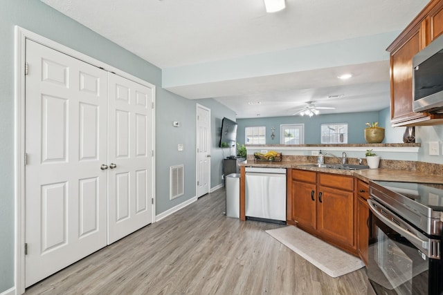 kitchen with stainless steel appliances, sink, light hardwood / wood-style floors, and kitchen peninsula