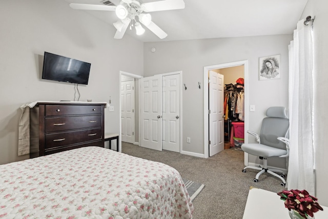 carpeted bedroom with vaulted ceiling, a walk in closet, and ceiling fan