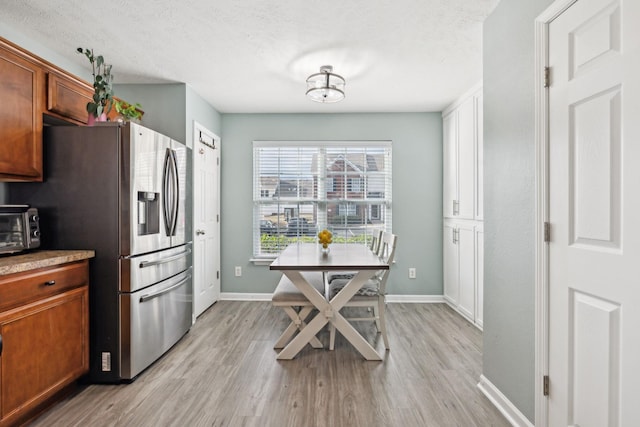 kitchen featuring light hardwood / wood-style floors, stainless steel fridge with ice dispenser, and a textured ceiling