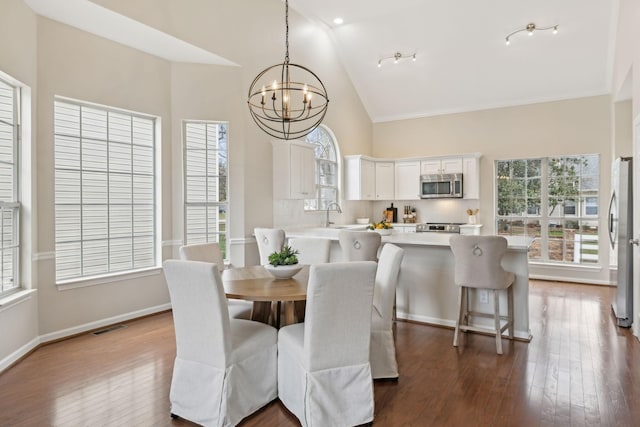 dining room with an inviting chandelier, hardwood / wood-style floors, high vaulted ceiling, and sink