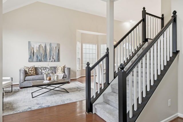 staircase with wood-type flooring and high vaulted ceiling