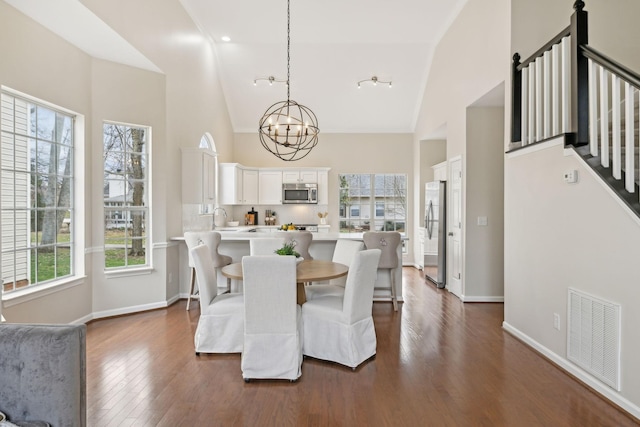 dining space featuring high vaulted ceiling, sink, a notable chandelier, and dark hardwood / wood-style flooring