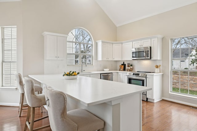 kitchen with sink, white cabinetry, a kitchen breakfast bar, stainless steel appliances, and kitchen peninsula