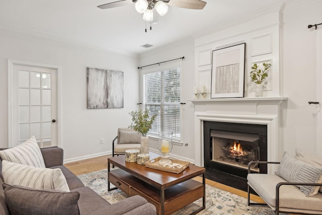 living area with crown molding, ceiling fan, and light hardwood / wood-style floors