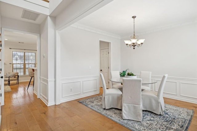 dining area featuring crown molding, light hardwood / wood-style floors, and a notable chandelier