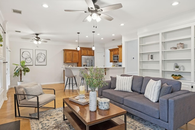 living room with light hardwood / wood-style flooring, ornamental molding, and ceiling fan