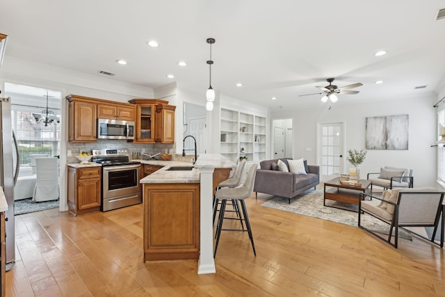 kitchen featuring sink, hanging light fixtures, a kitchen breakfast bar, kitchen peninsula, and stainless steel appliances