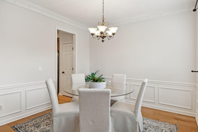 dining room with an inviting chandelier, hardwood / wood-style flooring, and ornamental molding