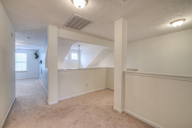 additional living space with light colored carpet and a textured ceiling