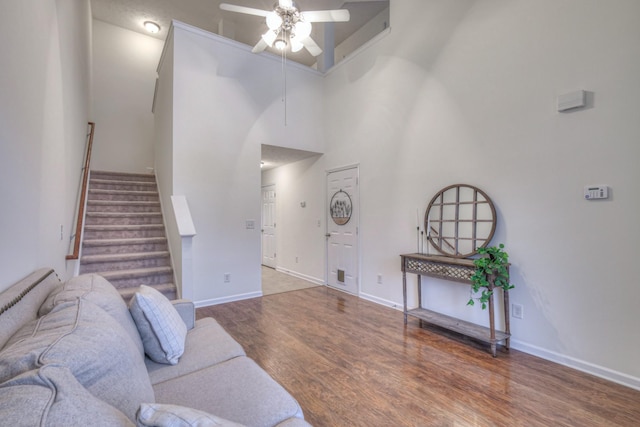 living room featuring hardwood / wood-style flooring, a towering ceiling, and ceiling fan