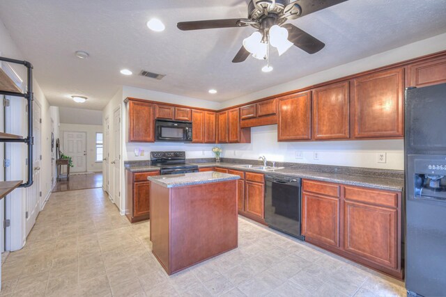 kitchen featuring ceiling fan, a center island, sink, and black appliances