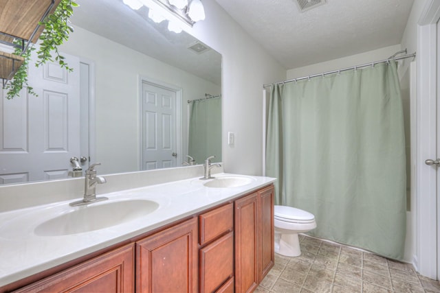 bathroom with vanity, a textured ceiling, toilet, and walk in shower