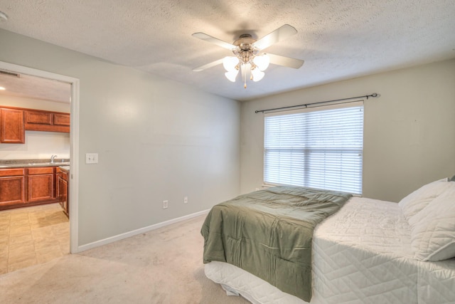 carpeted bedroom featuring ceiling fan, sink, and a textured ceiling