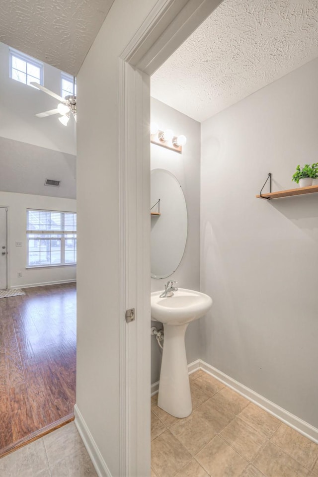 bathroom featuring ceiling fan, plenty of natural light, and a textured ceiling