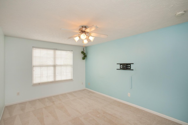 spare room with ceiling fan, light carpet, and a textured ceiling