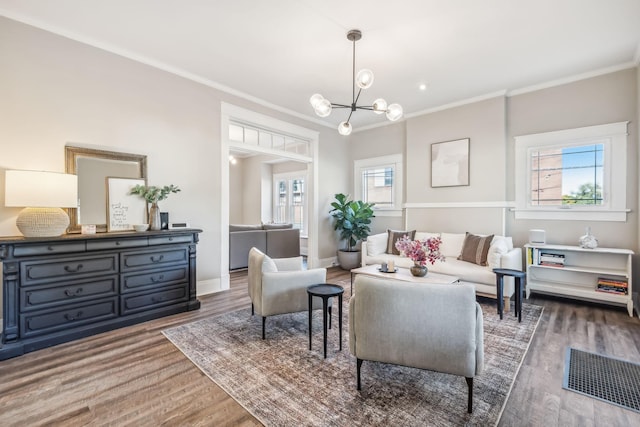 living room with dark wood-type flooring, ornamental molding, and an inviting chandelier