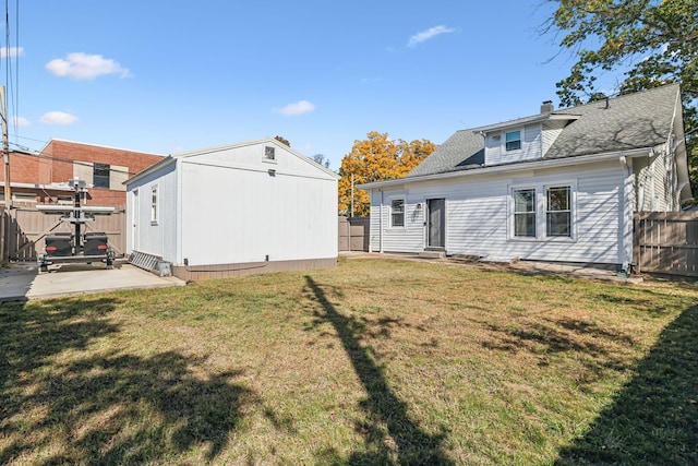 rear view of house with an outbuilding, a lawn, and a patio