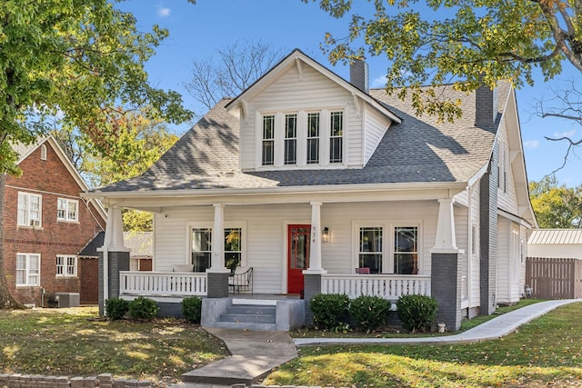 view of front of house with a porch, a front yard, and central air condition unit