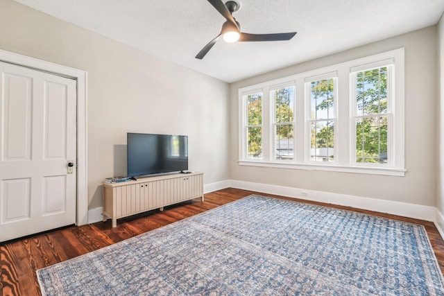 living room with dark hardwood / wood-style flooring, ceiling fan, and a textured ceiling