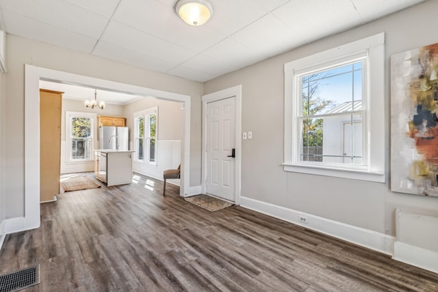 foyer featuring dark wood-type flooring, a paneled ceiling, and a notable chandelier