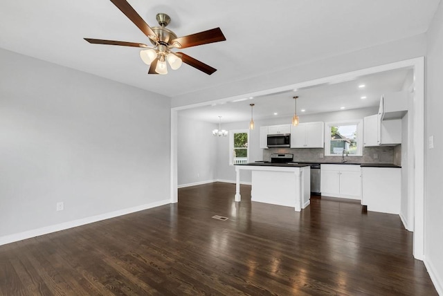 kitchen with white cabinetry, decorative light fixtures, a kitchen island, stainless steel appliances, and backsplash