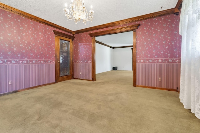 carpeted empty room featuring crown molding, a chandelier, and a textured ceiling