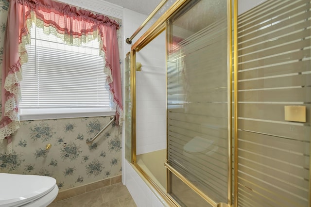 bathroom featuring toilet, shower / bath combination with glass door, and tile patterned flooring