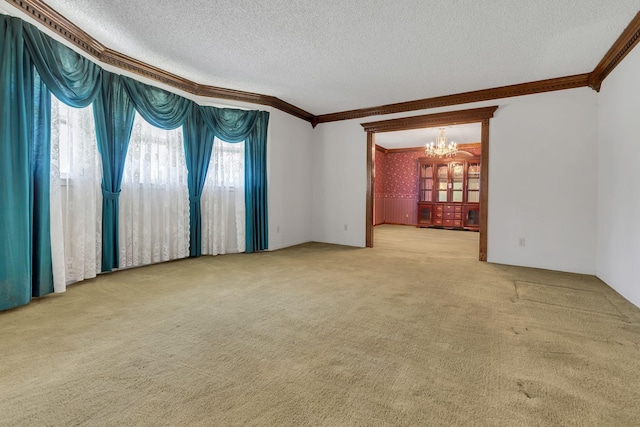 carpeted spare room with ornamental molding, a chandelier, and a textured ceiling