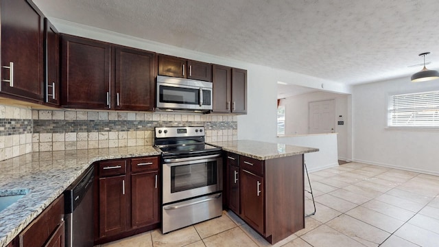 kitchen with stainless steel appliances, tasteful backsplash, light stone countertops, decorative light fixtures, and kitchen peninsula