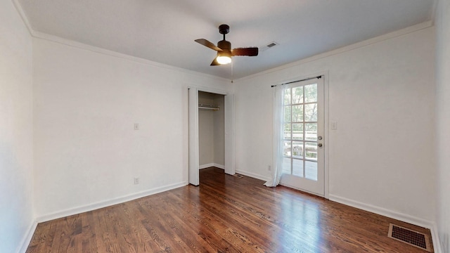 unfurnished bedroom with crown molding, dark wood-type flooring, a closet, and ceiling fan