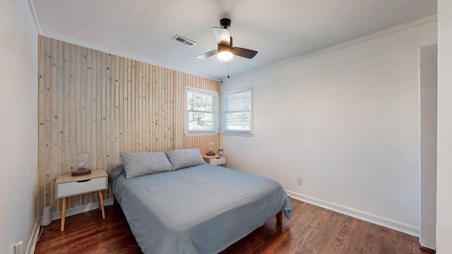 bedroom featuring dark hardwood / wood-style flooring, wooden walls, and ceiling fan