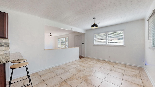 tiled spare room with a textured ceiling and a wealth of natural light