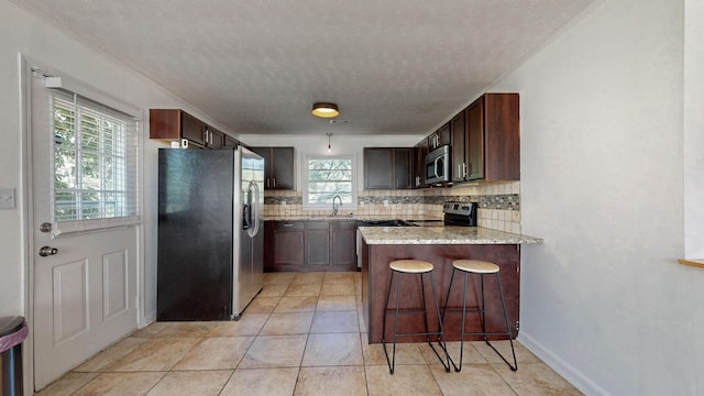 kitchen with tasteful backsplash, stainless steel appliances, a kitchen breakfast bar, and kitchen peninsula