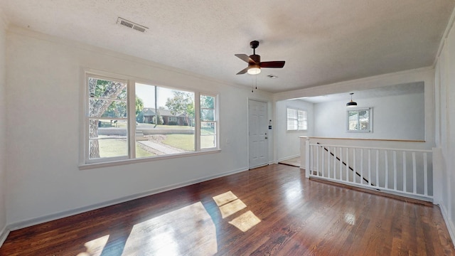 empty room featuring ceiling fan, dark wood-type flooring, and a textured ceiling