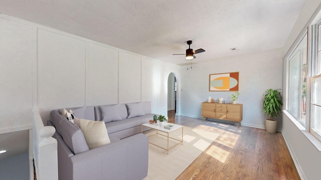 living room with a textured ceiling, wood-type flooring, and ceiling fan