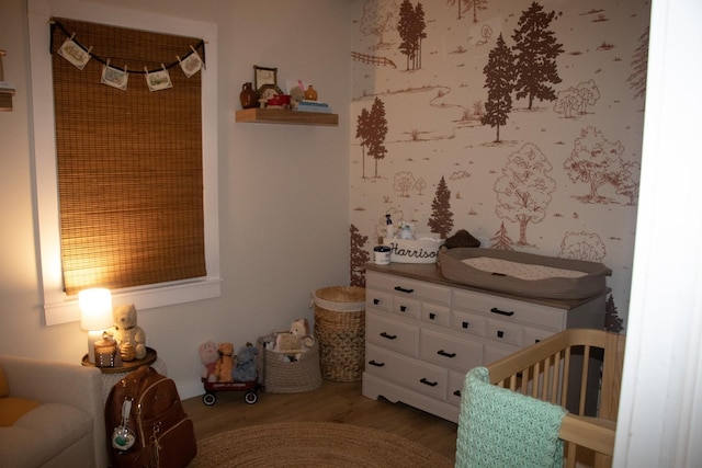 bedroom with wood-type flooring and a nursery area