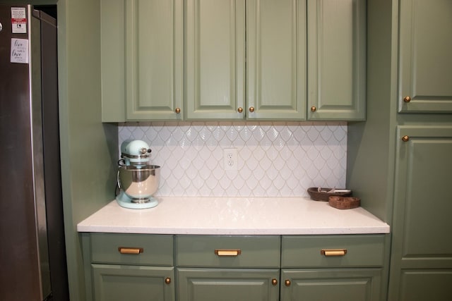 kitchen featuring tasteful backsplash, stainless steel fridge, and green cabinetry