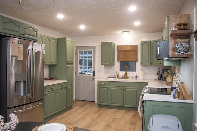 kitchen with stainless steel refrigerator with ice dispenser, sink, green cabinetry, range, and light hardwood / wood-style floors