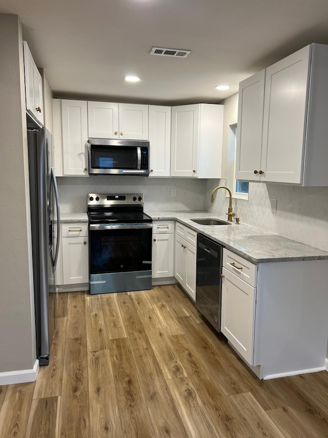 kitchen with visible vents, a sink, light wood-style floors, appliances with stainless steel finishes, and white cabinets