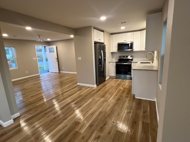 kitchen featuring sink, hardwood / wood-style flooring, stainless steel appliances, and white cabinets