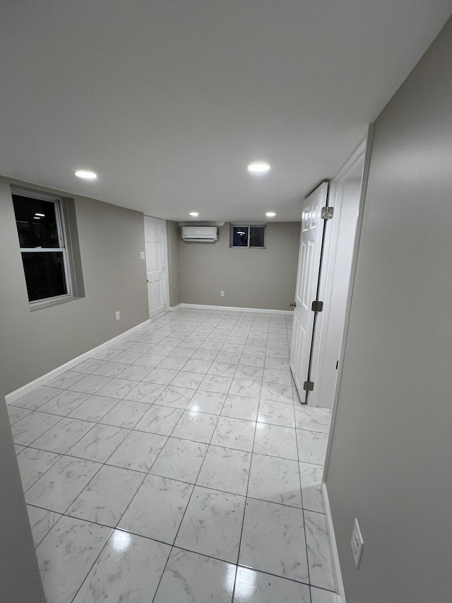 finished below grade area featuring recessed lighting, baseboards, marble finish floor, and a wall mounted air conditioner