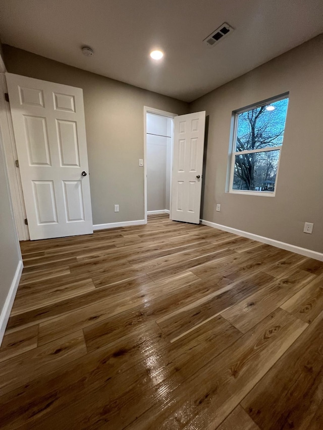 unfurnished bedroom featuring visible vents, baseboards, and wood finished floors