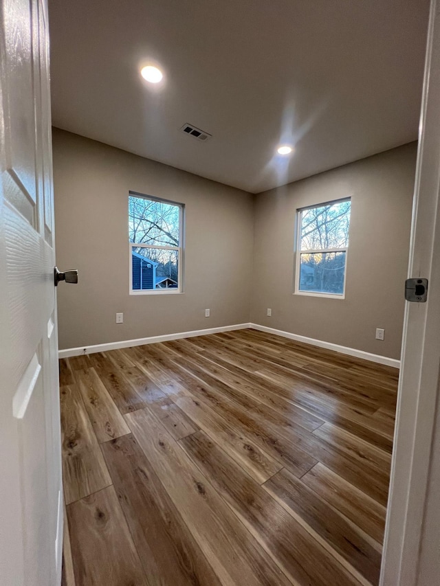 unfurnished bedroom featuring multiple windows, wood finished floors, and visible vents