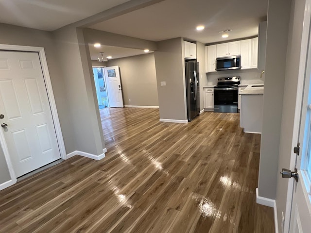 kitchen featuring dark wood finished floors, white cabinets, baseboards, and stainless steel appliances